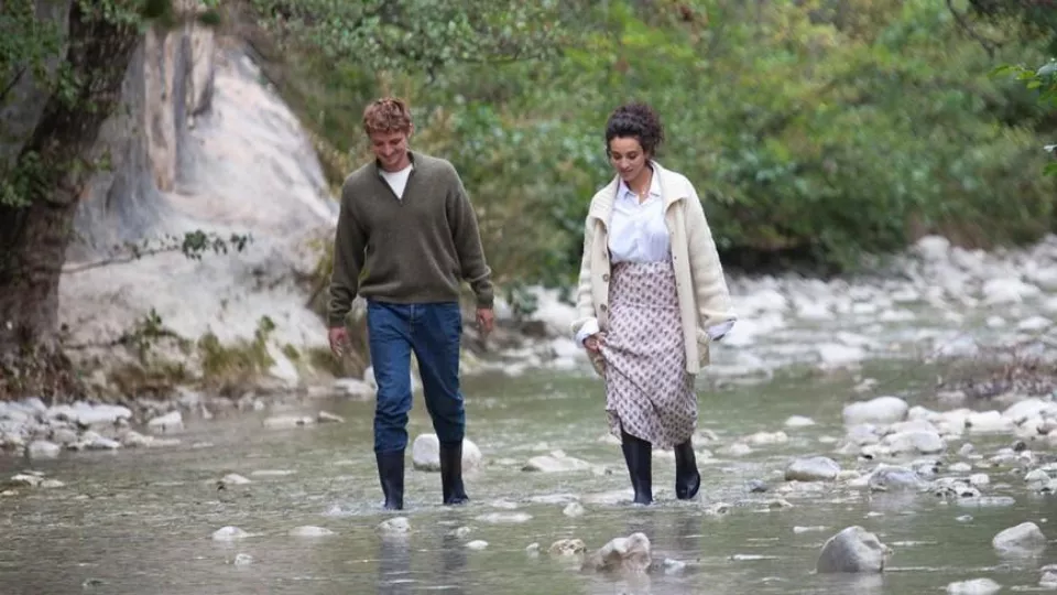 Dies ist das Filmplakat - Es zeigt einen Mann und eine Frau, die nebeneinander gehen und ihre Füße im Wasser eines Flusses haben.